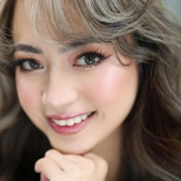 Close-up portrait with pink eye makeup, long lashes, rosy cheeks and softly curled hair