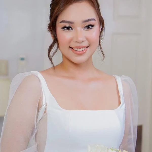Woman in a white dress with sheer sleeves, an updo and softly shimmering eye makeup
